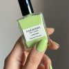 Eine Hand erischtlich, die die grüne Nagellack Flasche von Nailberry hält. Die Farbe vom Nagellack ist Hellgrün.