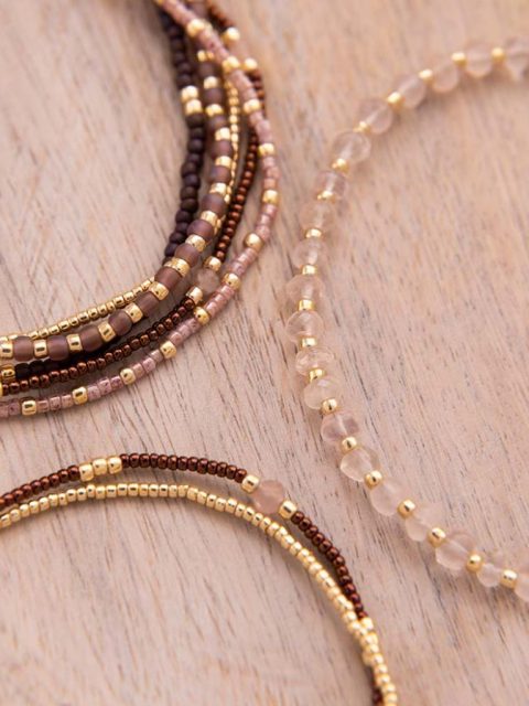 Nahaufnahme von Armband in Rosa, Gold und Rot-Violetten Tönen mit kleinen Anhänger in Gold