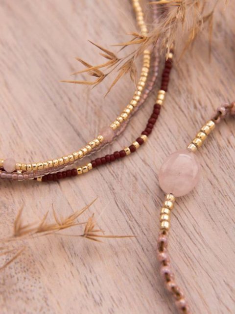 Nahaufnahm von handgemachtem Schmuck aus Nepal mit Perlen in Gold, Rosa und Dunkelrot. Kleiner Anhänger