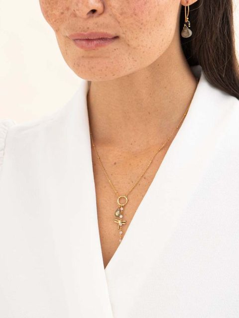 Auf dem BIld ist ein Modell mit einer langen Halskette in Gold mit drei Anhänger. Der eine Anhänger ist eine kleine Libelle, der andere Anhänger ist eine Ankettung von Mondsteinen und der andere Anhänger ist ein grosser Labradorit Anhänger. Handgemacht von der Marke a beautiful story