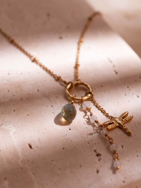 Schönes Stimmungsbild von langer Halskette in Gold mit drei Anhänger. Der eine Anhänger ist eine kleine Libelle, der andere Anhänger ist eine Ankettung von Mondsteinen und der andere Anhänger ist ein grosser Labradorit Anhänger. Handgemacht von der Marke a beautiful story