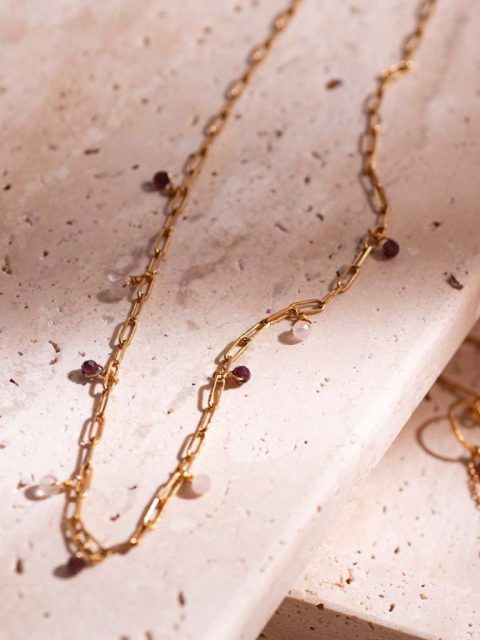 Lange Halskette aus goldigen Kettenmuster. Die Kette hat mehrere kleine Granat und Rose Quartz Anhänger. Die Kette ist handgemacht von der Marke a beautiful story