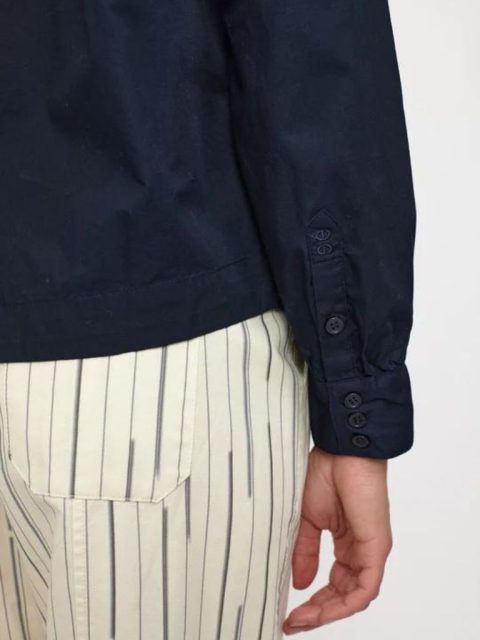 Nahaufnahme von dunkelblauer Bluse mit Knöpfen an den Ärmeln