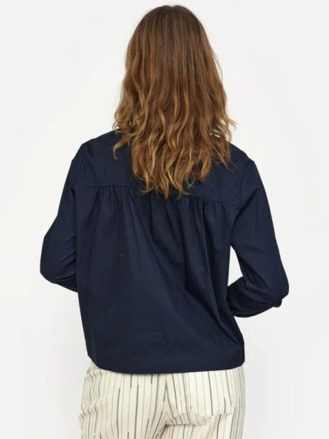 Modell von hinten ersichtlich, die eine dunkelblaue Bluse trägt