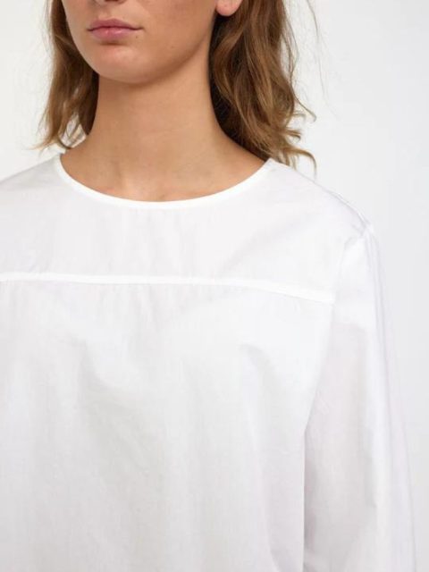 Nahaufnahme von Modell, die eine klassische weisse Bluse trägt. Das Modell sieht man nur von der Nase abwärts. Sie hat einen gleichgültigen Ausdruck