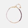 Armband mit kleinen Edelsteinen in Rosa, Rot und Gold. Das Armband hat einen Goldverschluss.