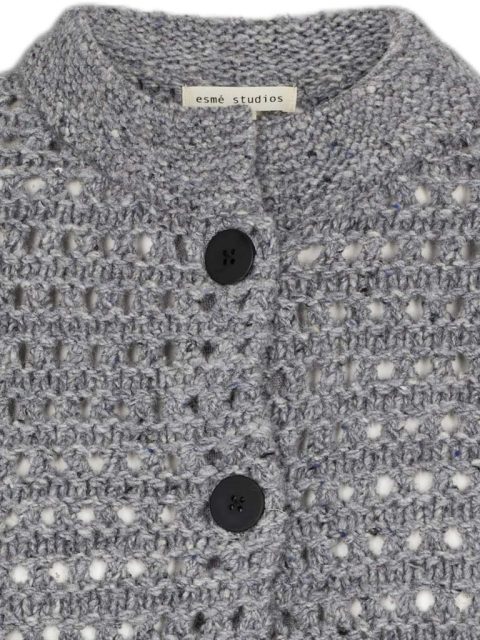 Nahaufnahme von grob gestricktem Cardigan in Grau mit dunklen Knöpfen.
